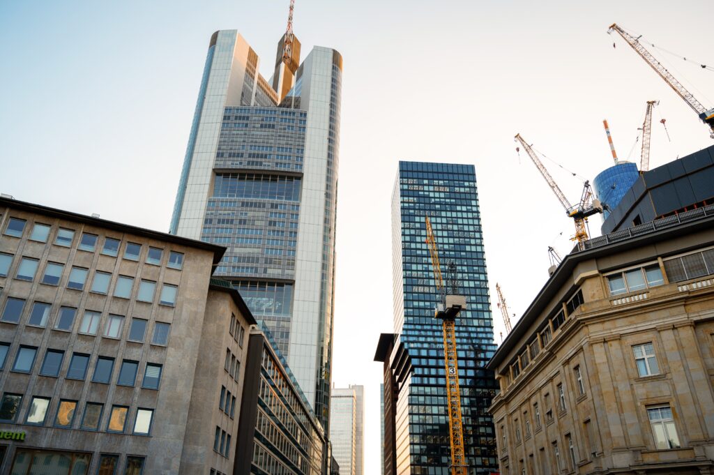 Modern skyscrapers and construction cranes in a cityscape at sunset.