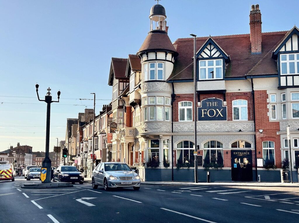 Historic building and traffic on a sunny day in Palmers Green, near local builders and renovation services.