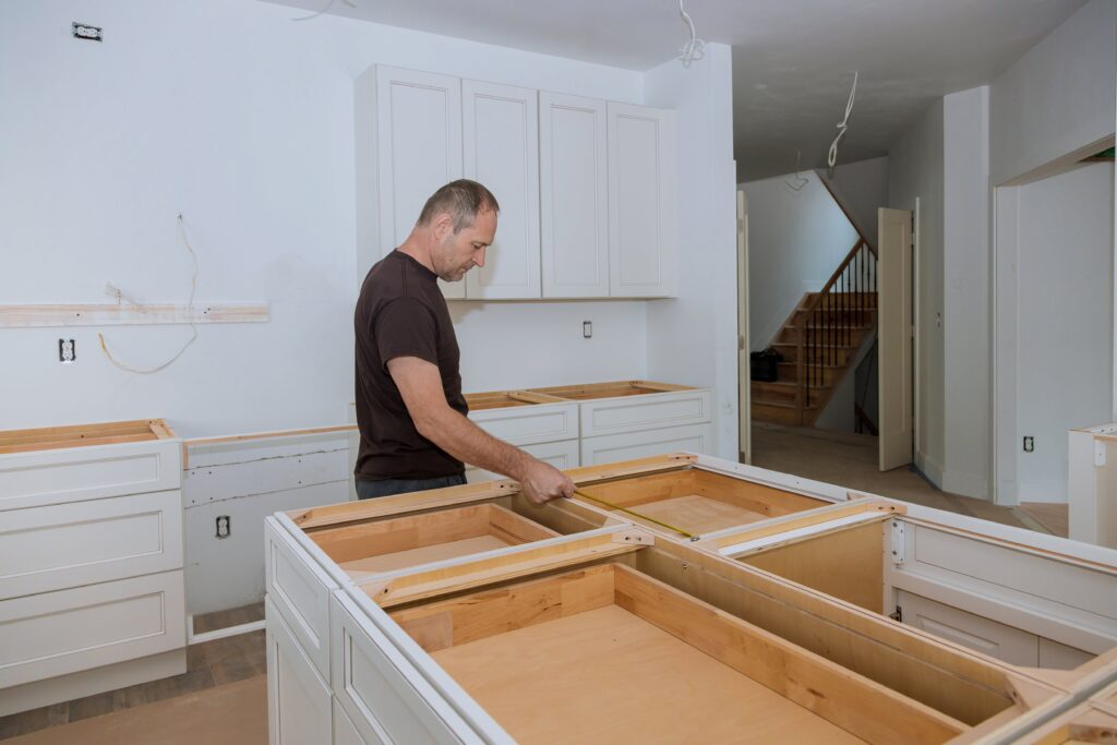 A man measuring a kitchen cabinet for a kitchen renovation